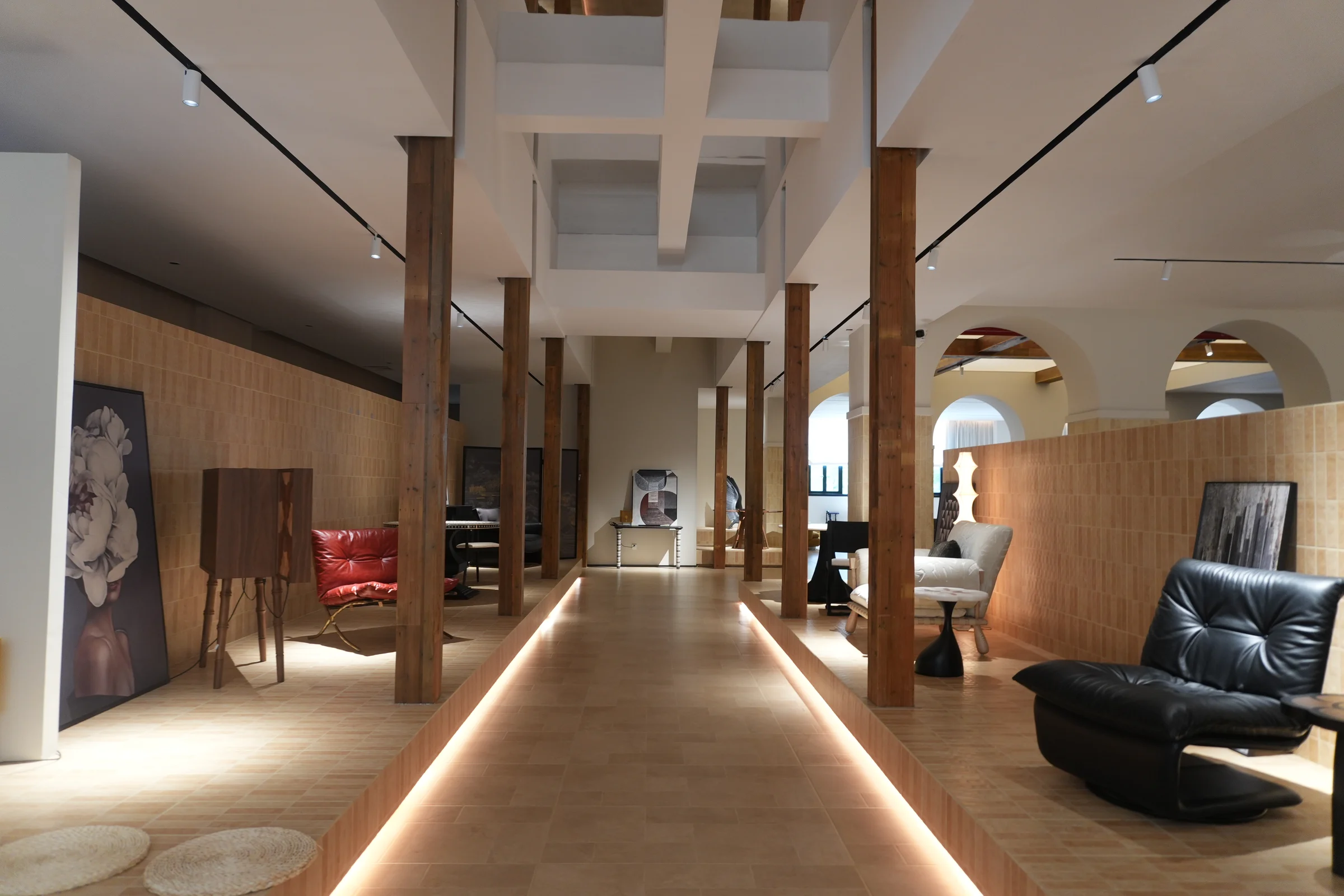 Timber-lined furniture gallery with illuminated walkways, cabinets and lounge chairs